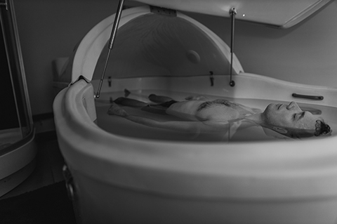 Relaxed man is floating in a sensory deprivation tank. He is very relaxed. Wellness and Spa concept.